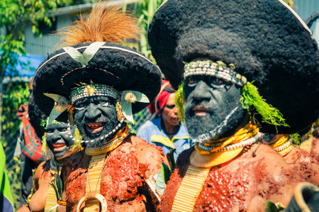 Wabag, Papua New Guinea - August 2015: Native half-naked men with large black hats and black colour on faces and mud on bodies pose to photocamera during Enga cultural show in Wabag, capital of Enga Province, Papua New Guinea. Documentary editorial.のeditorial素材