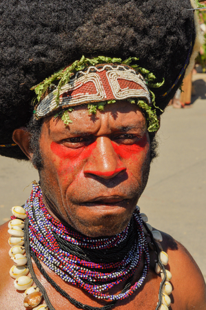 Wabag, Papua New Guinea - August 2015: Native man with red colour on face wears headband and large necklaces during Enga cultural show in Wabag, capital of Enga Province, Papua New Guinea. Documentary editorial.のeditorial素材