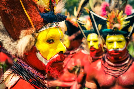Wabag, Papua New Guinea - August 2015: Photo of profile of native man with red and yellow colour on his face and body wearing large hat made of feathers and necklaces made of beads during performance at traditional Enga cultural show in Wabag, capital of のeditorial素材