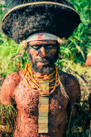 Wabag, Papua New Guinea - circa August 2015: Native half-naked man wears large black hat and yellow necklace during traditional Enga cultural show in Wabag, Papua New Guinea. Documentary editorial.のeditorial素材