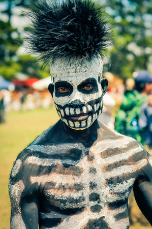 Hagen show, Papua New Guinea - circa August 2015: Native man with black and white colour on his body in form of skeleton wears fur cap during Hagen show, Papua New Guinea. Documentary editorial.のeditorial素材