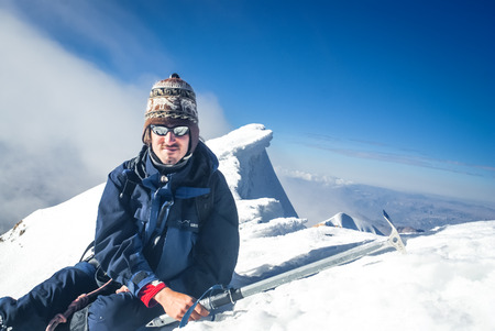 Huayna Potosi, Bolivia - May 2009: Mountaineer with sunglasses and knitted cap poses and smiles to photocamera at snowy top of Huayna Potosi, mountain in Bolivia, South America. Documentary editorial.の写真素材