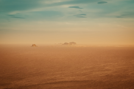 Hills and cliffs surrounded by sea covered in fog in distance near Vaeroy in Norway.の写真素材
