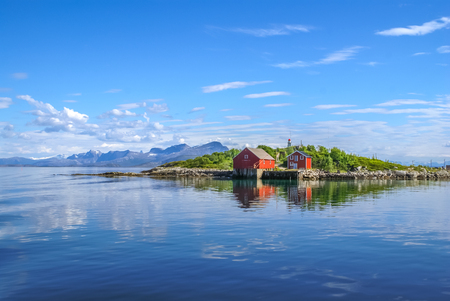 Photo of lake and coast with red wooden houses from ferry to Svolvaer in Norway.の写真素材