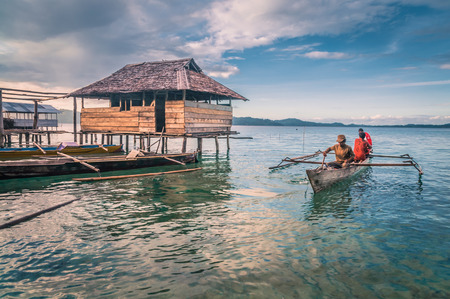 Sulawesi, Indonesia - May 2015: Photo of native men in wooden fishing boat near shore in Malange in Togean islands in Sulawesi, Indonesia. Documentary editorial.のeditorial素材