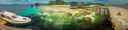 West Papua, Indonesia - May 2015: Panoramic photo of sea with white boat and wooden jetty on Arborek island in Raja Ampat, West Papua, Indonesia. Documentary editorial.のeditorial素材