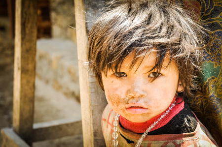 Kanchenjunga Trek, Nepal - circa May 2012: Photo of small brown-haired girl in pink shirt with dirt on her face and with necklace made of beads in Kanchenjunga Trek, Nepal. Documentary editorial.のeditorial素材