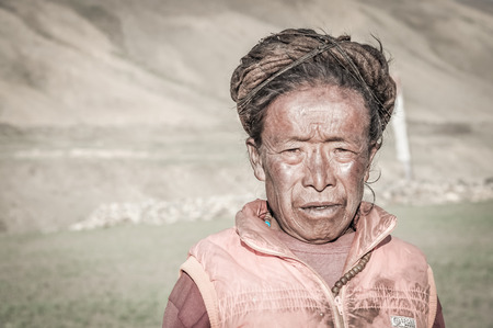 Dolpo, Nepal - circa June 2012: Old native woman with brown dreadlocks wears orange shirt in Dolpo, Nepal. Documentary editorial.のeditorial素材