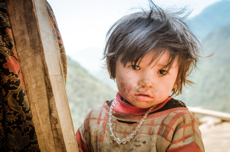 Kanchenjunga Trek, Nepal - circa May 2012: Small brown-haired girl with dirt on her face and with necklace made of beads poses in Kanchenjunga Trek, Nepal. Documentary editorial.のeditorial素材