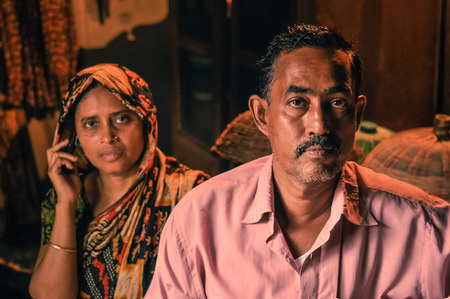 Morolgang, Bangladesh - circa July 2012: Black-haired man with moustache dressed in pink shirt with his wife with colourful headcloth in Morolgang, Bangladesh. Documentary editorial.のeditorial素材