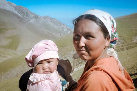 Arslanbob, Kyrgyzstan - circa July 2011: Native woman poses with her daughter in Arslanbob, Kyrgyzstan. Documentary editorial.のeditorial素材