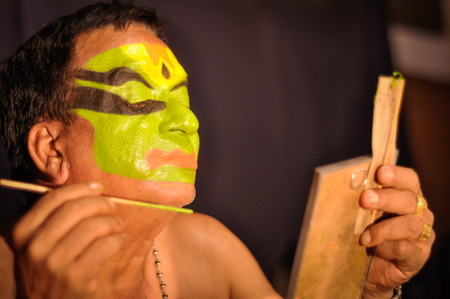 Ernakulam, Kerala - circa February 2012: Man paints his face with colours and looks to mirror at See India Foundation and prepares for Kathakali in Ernakulam, Kerala. Documentary editorial.のeditorial素材