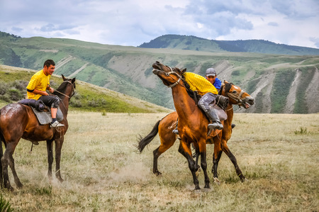 Karakol, Kyrgyzstan - circa July 2011: Young men wrestle on horseback at Karakol festival in Kyrgyzstan. Wrestling on horseback, traditonally called oodarysh. Documentary editorial.のeditorial素材