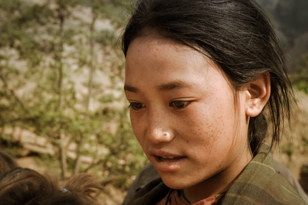 Dolpo, Nepal - circa May 2012: Young black-haired girl with brown eyes looks down and talks in Dolpo, Nepal. Documentary editorial.のeditorial素材