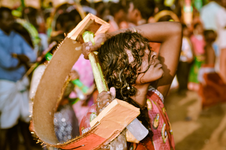 Alleppey, Kerala - circa February 2012: Photo of young woman with closed eyes holding wooden object behind her head during festival in Alleppey, Kerala. Documentary editorial.のeditorial素材
