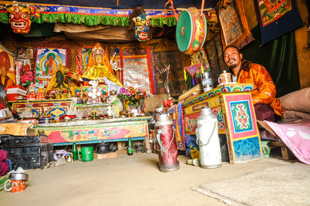 Dolpo, Nepal - circa May 2012: Small child in blue sweater with green necklace and cap with coins has dirt on face with cake in hand in Dolpo, Nepal. Documentary editorial.のeditorial素材