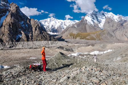 South Inylchek Glacier, Kyrgyzstan - circa August 2011: Tourist dressed in orange t-shirt and headcloth poses with beautiful South Inylchek Glacier in background. Documentary editorial.のeditorial素材