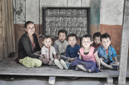Kanchenjunga Trek, Nepal - circa May 2012: Teacher sits with children on ground during learning of letters of alphabet and they look to photocamera in Kanchenjunga Trek, Nepal.のeditorial素材