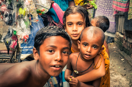 Khulna, Bangladesh - circa July 2012: Young brown-haired and brown-eyed children look curiously to photocamera in slum in Khula, Bangladesh. Documentary editorial.のeditorial素材