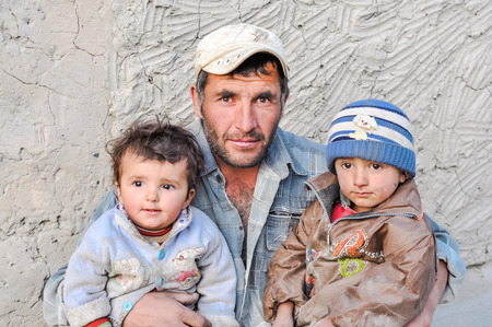 Khorog, Tajikistan - circa September 2011: Older man poses with his two small children in Khorog, Tajikistan. Documentary editorial.のeditorial素材