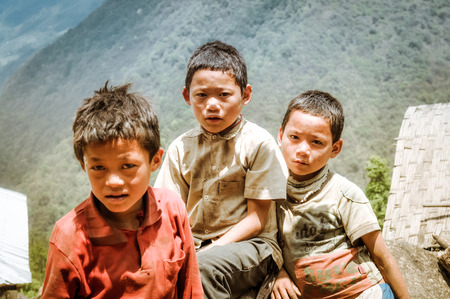 Kanchenjunga Trek, Nepal - circa May 2012: Three young brown-haired boys stand next to each other and look sadly to photocamera in Kanchenjunga Trek, Nepal. Documentary editorial.のeditorial素材