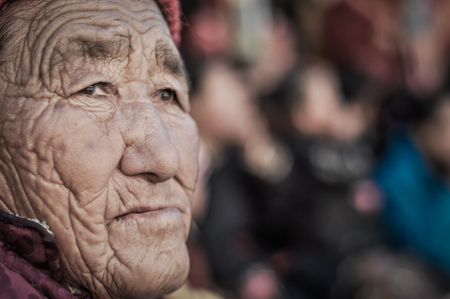 Thiksey, Ladakh - circa November 2011: Old woman with wrinkled tanned face watches ceremony at Thiksey festival, Ladakh. Documentary editorial.のeditorial素材