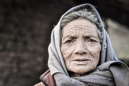 Dolpo, Nepal - circa May 2012: Old woman with wrinkles on her face and brown eyes wears grey headcloth in Dolpo, Nepal. Documentary editorial.のeditorial素材