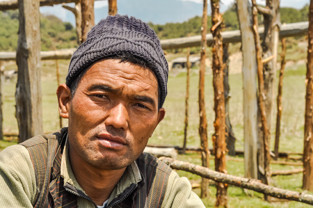 Beni, Nepal - circa May 2012: Native man with black knitted cap on his head in Beni, Nepal. In background with wooden construction. Documentary editorial.のeditorial素材
