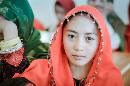 Afghanistan - circa October 2011: Native girl with orange hijab and serious sight at ADRA school in Afghanistan. Documentary editorial.のeditorial素材