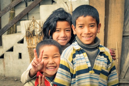 Ziro, Arunachal Pradesh - circa March 2012: Three young siblings smile and look to photocamera in Ziro, Arunachal Pradesh. Documentary editorial.のeditorial素材