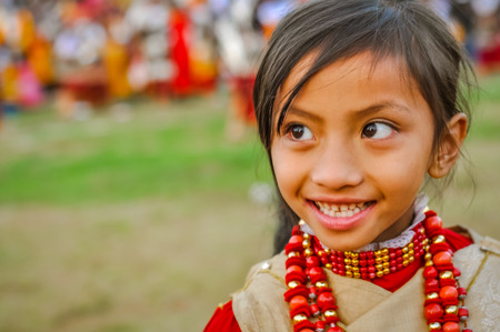 Shillong, Meghalaya - circa April 2012: Small brown-haired girl with red necklaces made of beads smiles and looks left at Shad Suk Mynsiem Festival in Shillong, Meghalaya. Documentary editorial.のeditorial素材