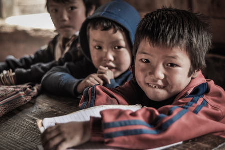 Dorjeling, Arunachal Pradesh - circa March 2012: Three young boys look curiously to photocamera at school in Dorjeling, Arunachal Pradesh. Documentary editorial.のeditorial素材