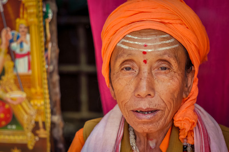 Ganga Sagar, West Bengal - circa January 2012: Older woman with three red dots and three white lines on her forehead wears orange turban in Ganga Sagar, West Bengal. Documentary editorial.のeditorial素材