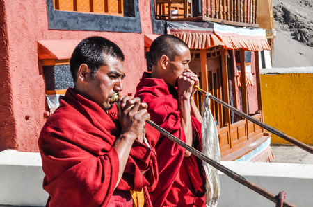 Thiksey, Ladakh - circa November 2011: Photo of two monks dressed in red blowing horns at roof at Thiksey monastery, Ladakh. Documentary editorial.のeditorial素材