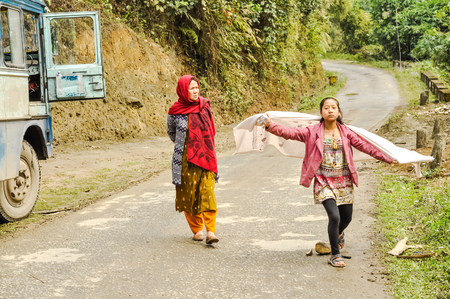 Daporijo, Arunachal Pradesh - circa March 2012: Photo of two native women walking down the road near Daporijo, Arunachal Pradesh. Documentary editorial.のeditorial素材