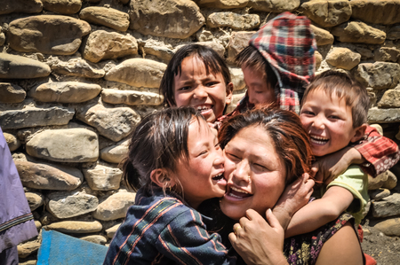 Dolpo, Nepal - circa June 2012: Young children hug their mother and smile joyfully to photocamera in Dolpo, Nepal. Documentary editorial.のeditorial素材