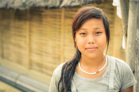 Damak, Nepal - circa May 2012: Young woman with long hair wears white shirt and necklace made of white beads at Nepali refugee camp in Damak, Nepal. Documentary editorial.のeditorial素材