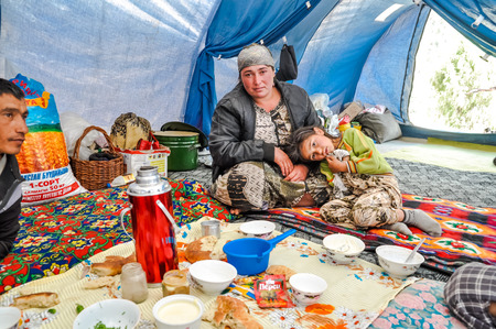 Arslanbob, Kyrgyzstan - circa July 2011: Native mother and daughter pose in big tent during lunch in Arslanbob, Kyrgyzstan. Documentary editorial.のeditorial素材