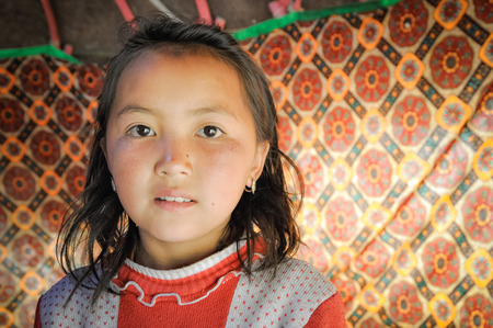 Arslanbob, Kyrgyzstan - circa July 2011: Young native girl with serious face poses in Arslanbob, Kyrgyzstan. Documentary editorial.のeditorial素材
