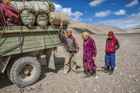 Karakul, Tajikistan - circa September 2011: Native people stand next to lorry with heavy load in Karakul, Tajikistan. Documentary editorial.のeditorial素材