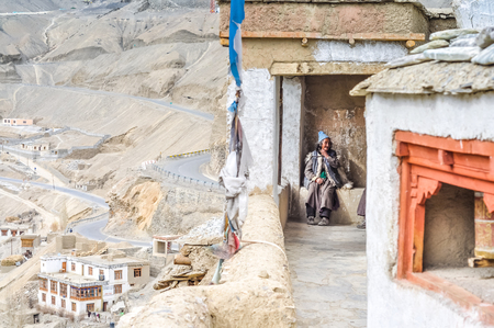 Lamayuru, Ladakh - circa November 2011: Old native woman with blue cap sits at Lamayuru monastery, Ladakh. On left side with interesting view of Lamayuru. Documentary editorial.のeditorial素材
