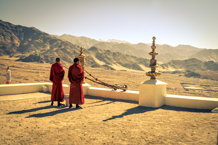 Thiksey, Ladakh - circa November 2011: Photo of two monks blowing horns at rooftop as morning ceremony at Thiksey monastery, Ladakh. In background with beautiful scenery. Documentary editorial.のeditorial素材
