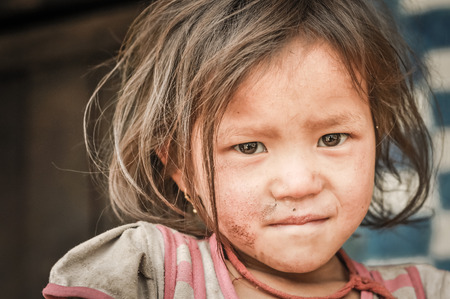 Kanchenjunga Trek, Nepal - circa May 2012: Small girl with short brown hair and dirt on her face in Kanchenjunga Trek, Nepal. Documentary editorial.のeditorial素材