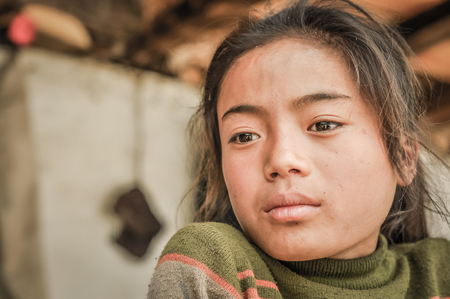 Kanchenjunga Trek, Nepal - circa May 2012: Young thinking girl in green sweater looks down in Kanchenjunga Trek, Nepal. Documentary editorial.のeditorial素材