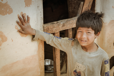 Dolpo, Nepal - circa May 2012: Young black-haired boy holds his hand on handprint on brown wall in Dolpo, Nepal. Documentary editorial.のeditorial素材
