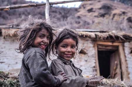 Kuari pass, Uttarakhand - circa December 2011: Young native girls with dust on their faces wear grey sweater and smile to photocamera in Kuari pass, Uttarkhand. Documentary editorial.のeditorial素材