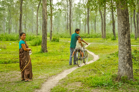 Damak, Nepal - circa May 2012: Young smiling boy poses half-naked with t-shirt on his head in greenery of Nepali refugee camp in Damak, Nepal. Documentary editorial.のeditorial素材