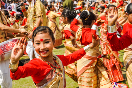Guwahati, Assam - circa April 2012: Dancing girl in red and yellow sari with red dot on forehead smiles during performance at traditional Bihu festival in Guwahati, Assam. Documentary editorial.のeditorial素材