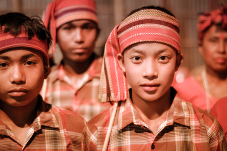 Guwahati, Assam - circa April 2012: Young native boys in orange costumes and with headbands look to photocamera at Bihu festival in Guwahati, Assam. Documentary editorial.のeditorial素材