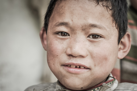 Kanchenjunga Trek, Nepal - circa May 2012: Photo of young boy with beautiful brown eyes looking to photocamera in Kanchenjunga Trek, Nepal. Documentary editorial.のeditorial素材